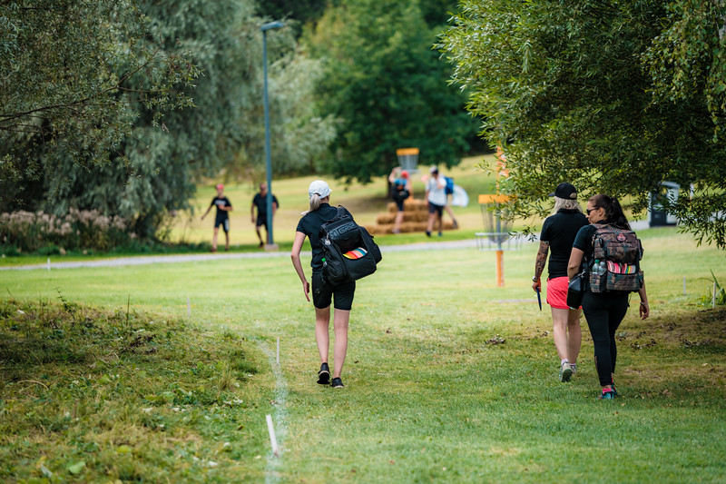 Disc golfers walking toward basket at a disc golf tournament