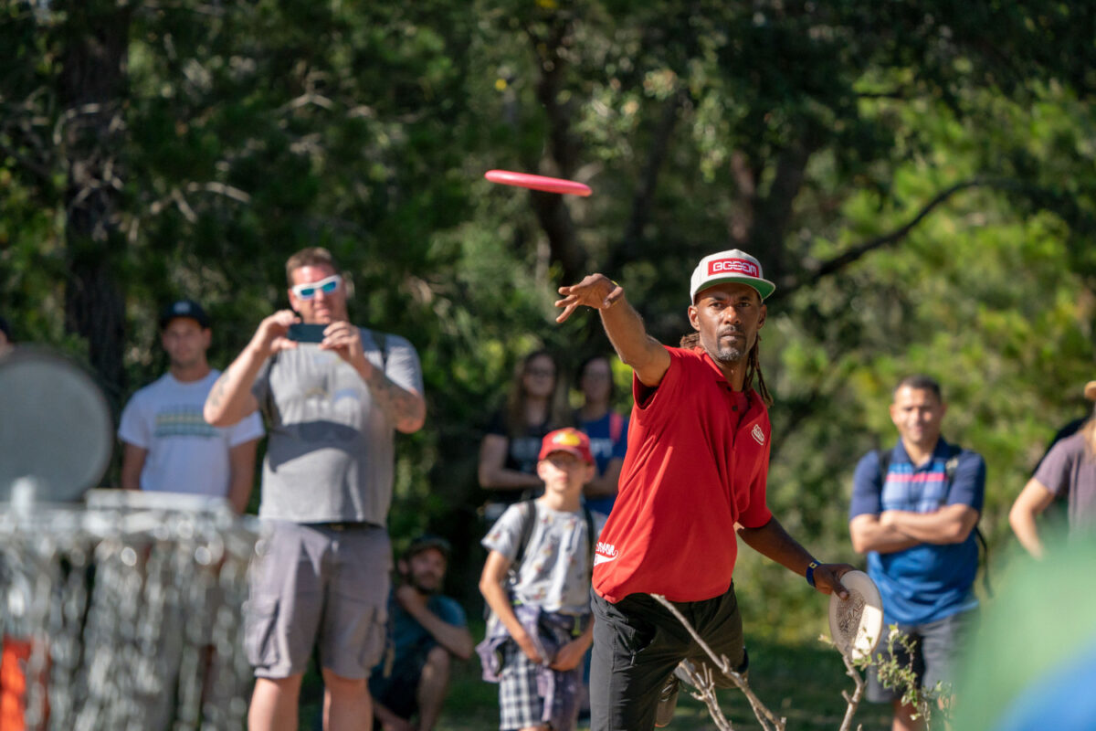 Philo Brathwaite releasing a putt at a disc golf tournament.